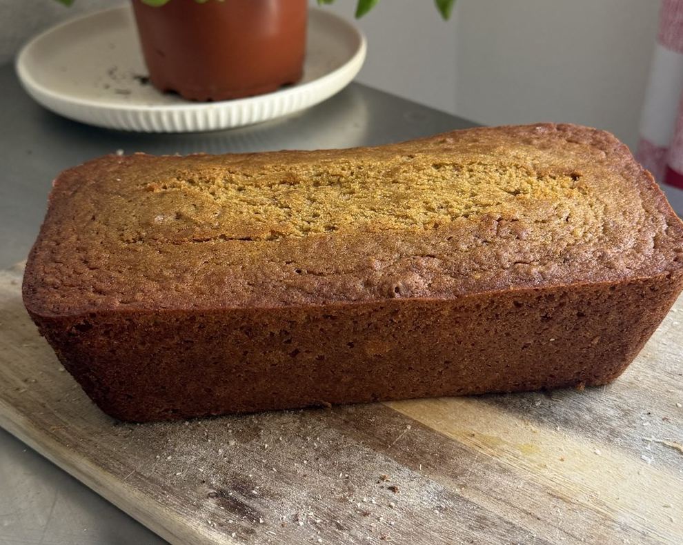 Whole golden-brown pumpkin bread loaf on a wooden cutting board