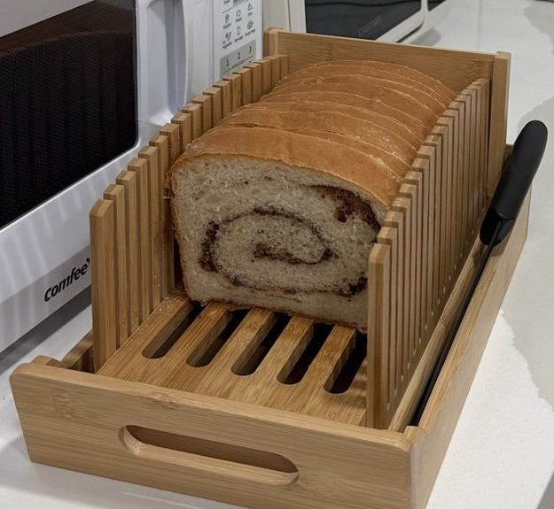 Sliced white bread showing a cinnamon swirl through the crumb, in a bamboo slicer